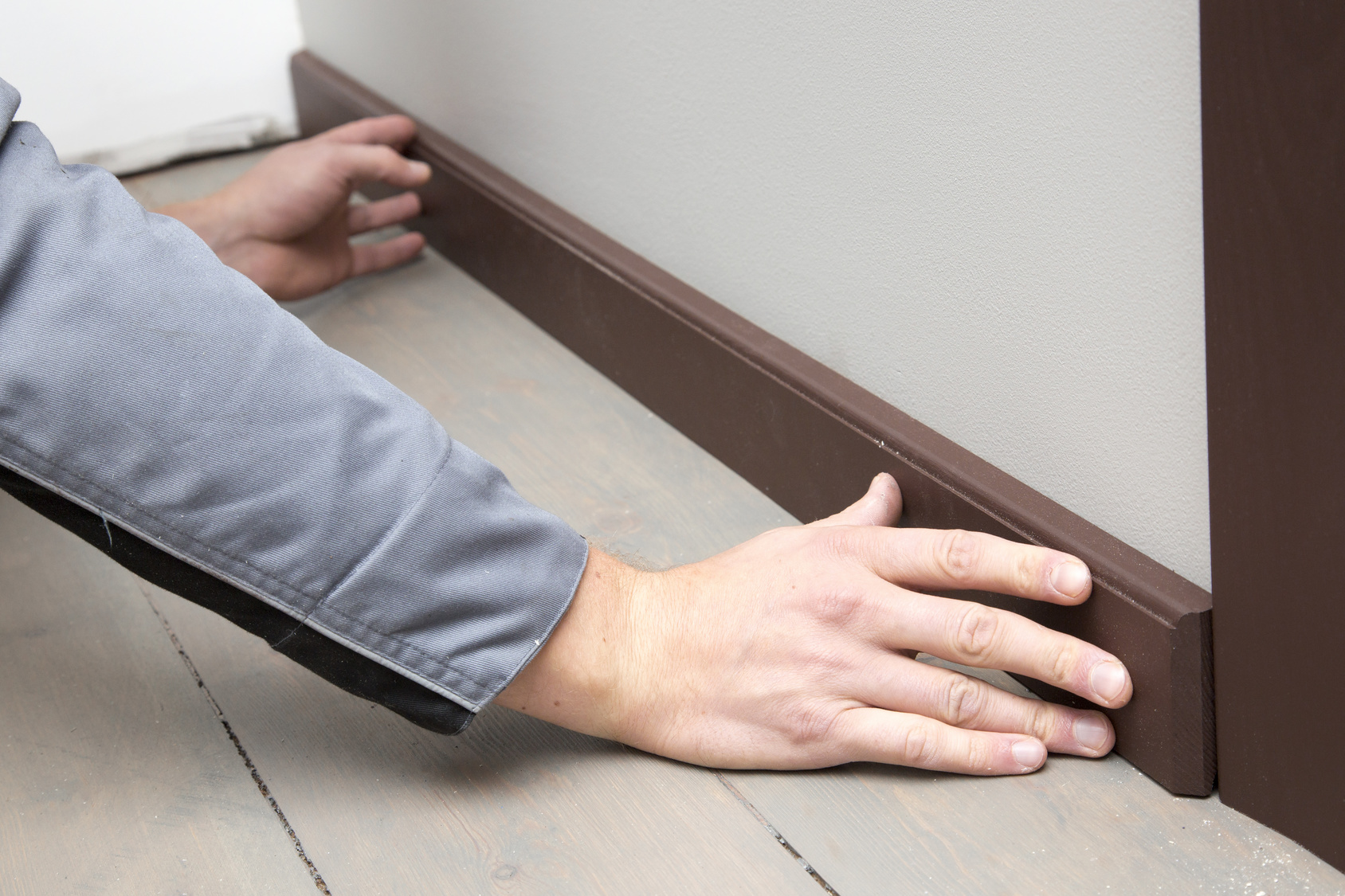 installation of a brown wooden baseboard at the bottom of the wa Waś